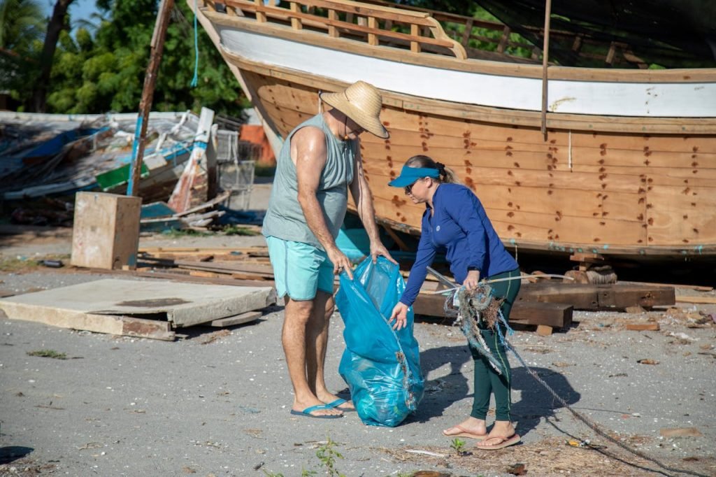 Man and woman engaged in beach cleanup near a boat in Brazil.