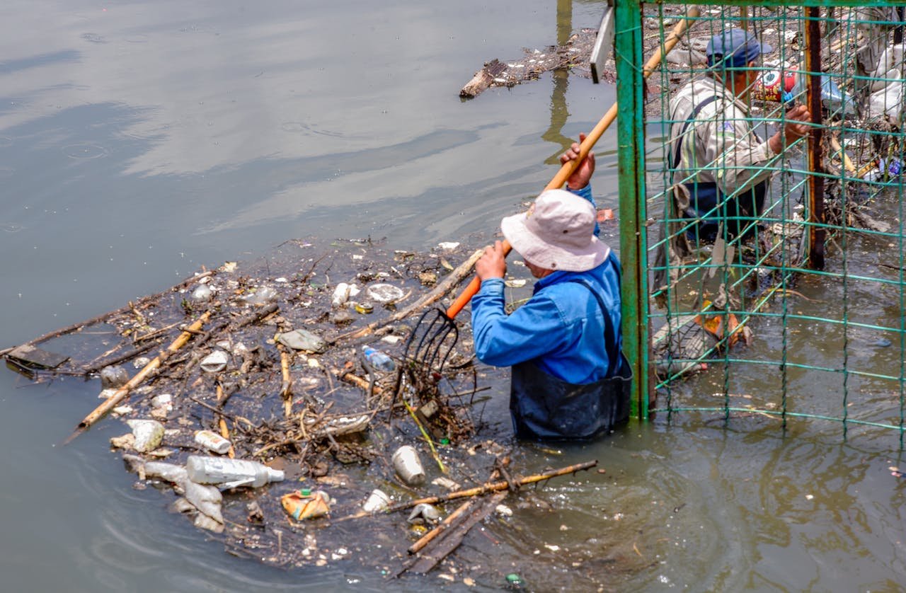 Men clearing debris from a garbage-polluted river. Environmental cleanup in action.